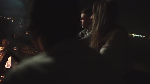 Young People Talking and Roasting Marshmallows by Campfire alt