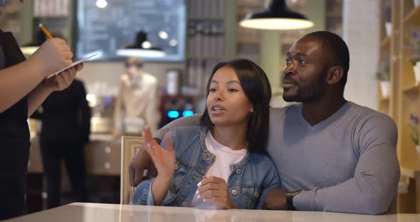 Happy Afroamerican Couple on Date Making Order in Cafe alt