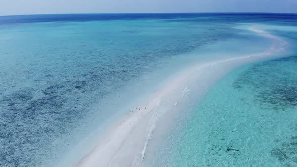 Cinematic reveal shot aerial view of long beach shoreline in a beautiful small beach