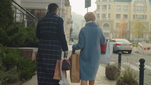 Rear View of Mature Women Carrying Many Shop Paper Packages Outdoors alt