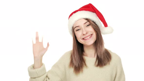 Happy Portrait of Attractive Young Woman in Santa Claus Red Hat Greeting People Waving Hand Enjoying alt