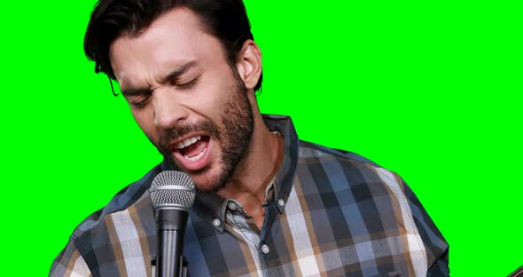 Male musician singing while playing guitar alt