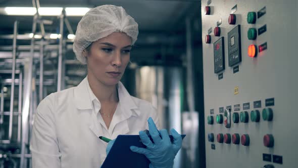 Female Factory Worker Check a Machine at a Dairy Factory. alt