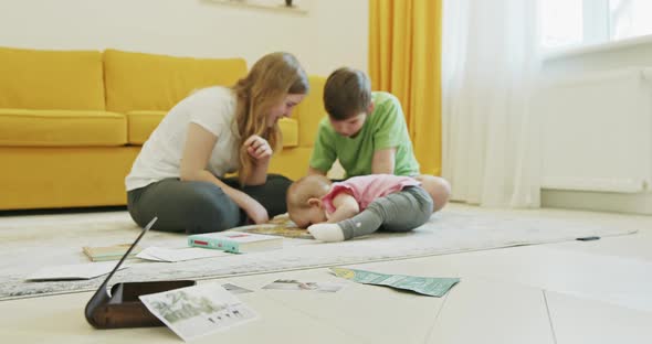 Siblings Trying To Study on Floor Near Baby alt