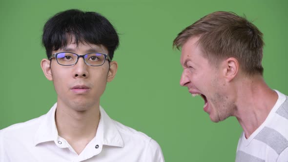 Young Angry Scandinavian Businessman Screaming at Young Asian Businessman alt