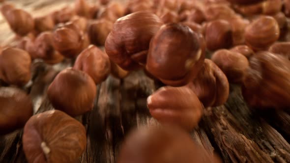 Super Slow Motion Detail Shot of Hazelnuts Rolling Towards on Wooden Background at 1000Fps alt