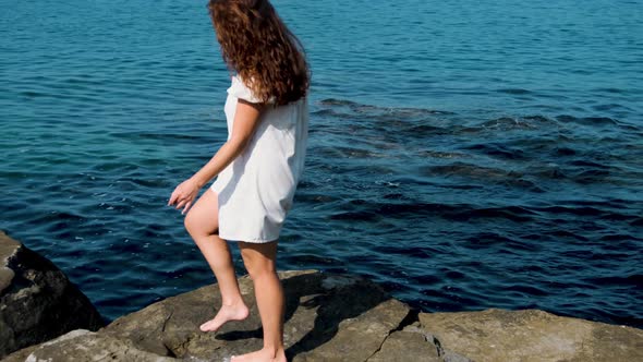 girl in a white sundress on the background of the sea on a bright sunny day