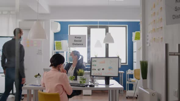 Business Woman with Medical Face Mask Talking on Smartphone with Partners alt