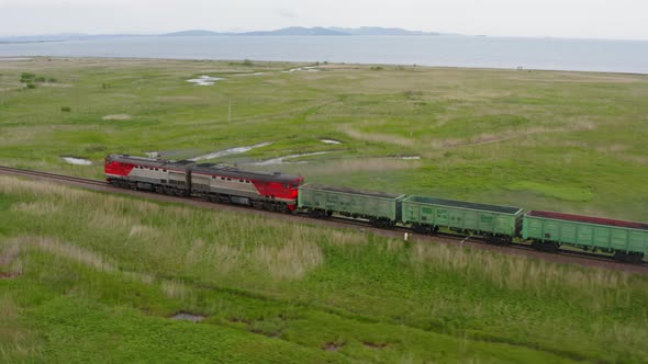 A Drone View of a Freight Train Driven By a Diesel Locomotive on a Railroad alt