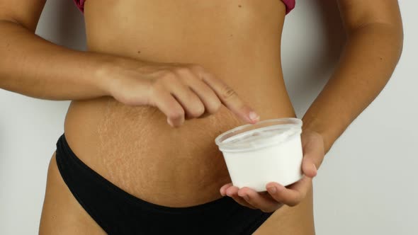 Beautiful girl smears her belly with cream. Sensitive hand massage. A woman after childbirth alt