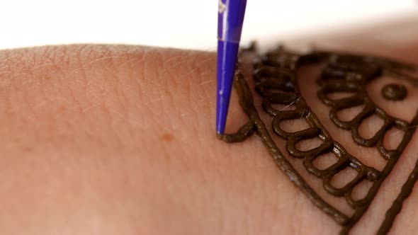 Womans Hand Being Decorated with Henna Tattoo, Mehendi, on White, Close Up alt