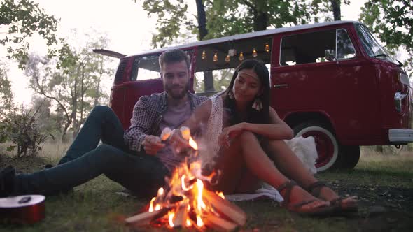Beautiful Young Couple Roasting Marshmallows Over a Campfire While Enjoying Their Road Travel Slow alt