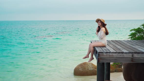 happy woman sitting on a wooden bridge in the sea beach at Koh MunNork Island, Rayong, Thailand alt