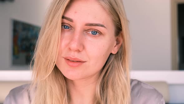 Young Alluring Blonde Woman with Blue Eyes Looks Peacefully Into the Camera  Slow Motion