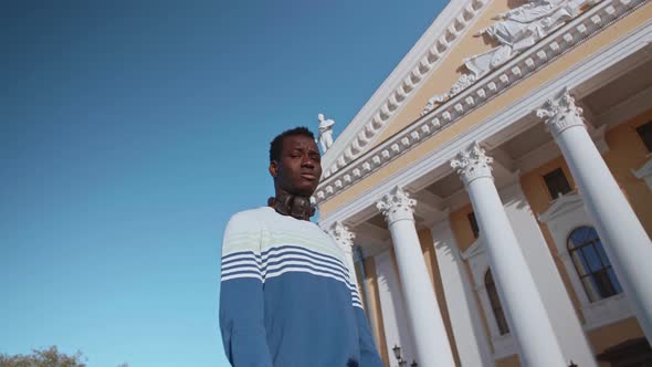 A Young Black Guy Poses Against the Backdrop of a Beautiful Theater Building