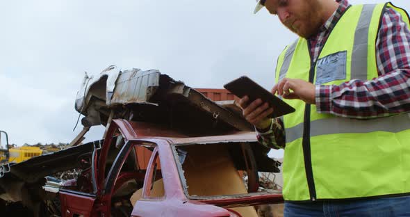 Male worker using digital tablet in the junkyard  alt