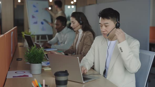 Focused Call Center Agent Using Laptop and Headset at Office alt