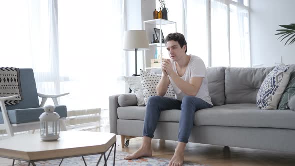 Upset Young Man in Tension Sitting on Sofa and Thinking alt