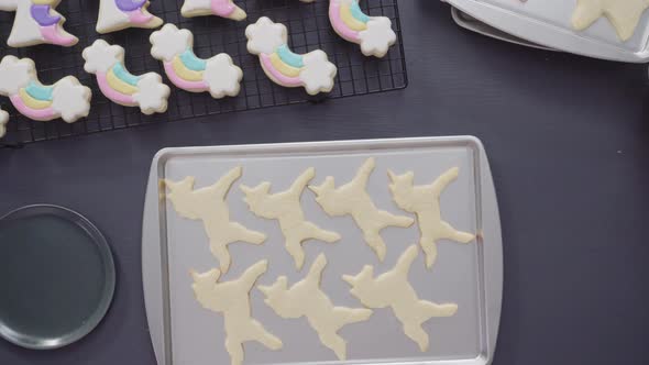 Step by step. Flat lay. Decorating unicorn sugar cookies with royal icing on baking sheet alt