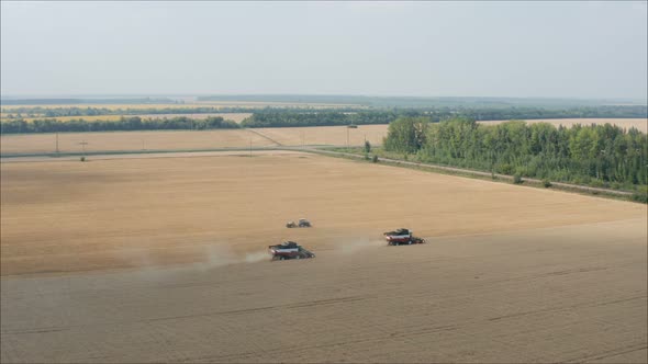 Harvesting of Wheat in Summer. Two Red Harvesters Working in the Field. Two Harvesters on the Field alt