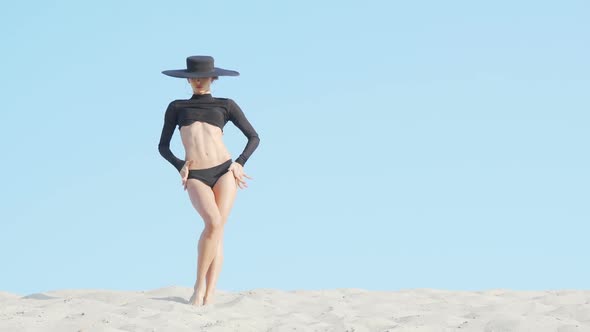 Stunning Elegant Woman in Big Black Hat Dancing on Sand alt