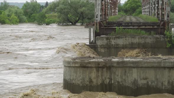 An Old Abandoned Bridge Over a River That Overflows. Stormy Water Flows. Extremely High Water Level
