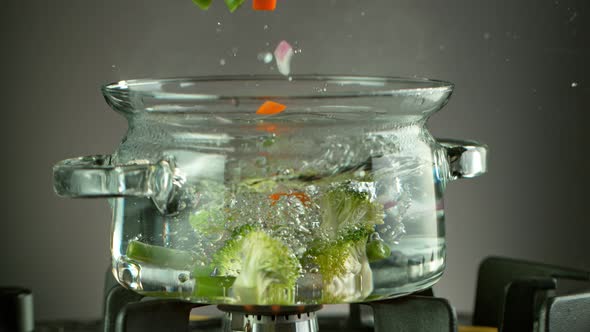 Super Slow Motion Shot of Fresh Vegetable Falling Into Boiling Salted Water at 1000 Fps. alt