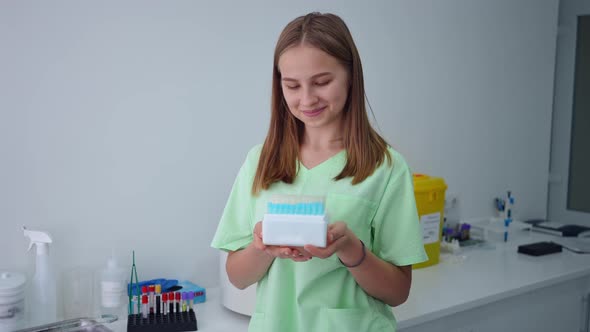 Portrait of Confident Charming Laboratory Assistant Posing with Box of Test Tubes Indoors alt