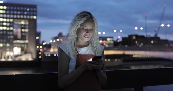Pretty young woman typing message on smartphone, London, UK
