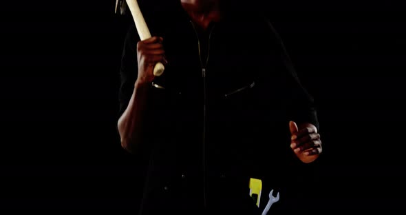 Androgynous man posing with hammer against black background alt
