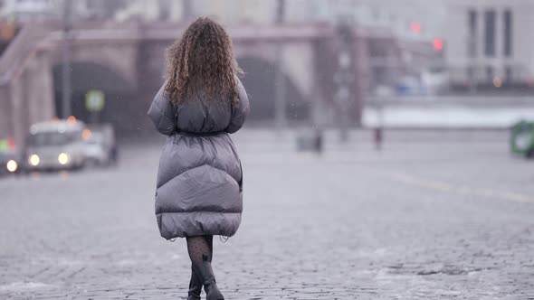 Lonely Woman is Walking Alone in City at Snowless Winter Grey Tones Cityscape alt