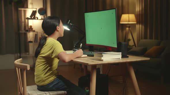 Asian Girl Student Distance Learning With Mock Up Computer Green Screen From Home alt