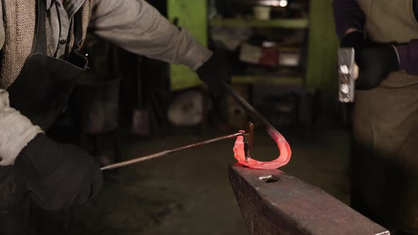 Two Blacksmiths Are Forging Iron Horseshoe in a Forge, Close-up alt