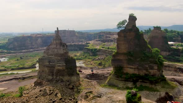 Passing two rock columns to reveal aerial panorama of Brown Canyon quarry, Java alt