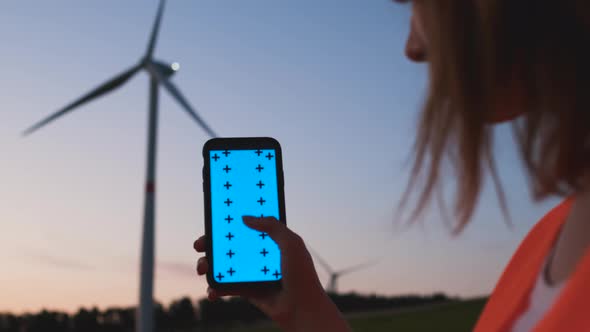 Woman Engineer Holding a Smartphone with Chroma Key and Making Scroll Down Gesture on the Background alt