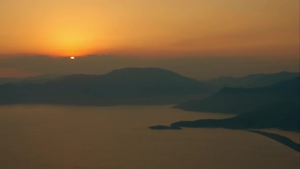 Aerial View of Sunset Over Quiet Sea Lagoon Surrounded By Mountains and Hills