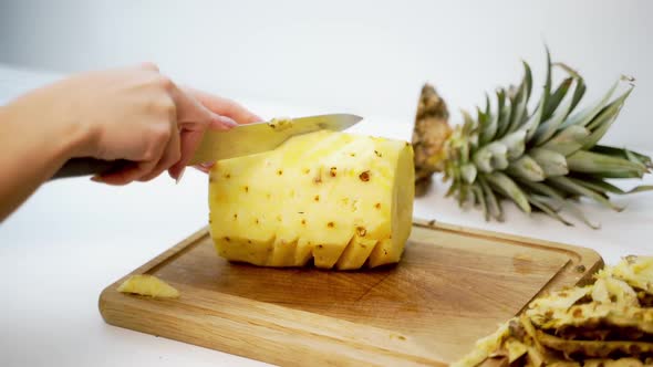 Hands slicing pineapple. Person slicing ripe pineapple with knife on table alt