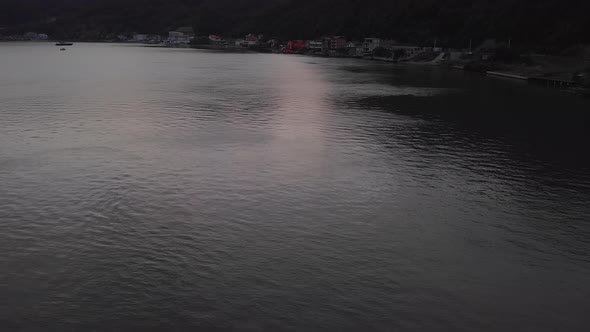 Beautiful reveal of a calm River Danube and small town at sunset. Romania. alt