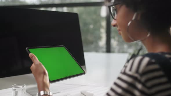 Over The Shoulder Shot Of a Business Woman Working In Office Interior On Tablet, Looking At Display alt