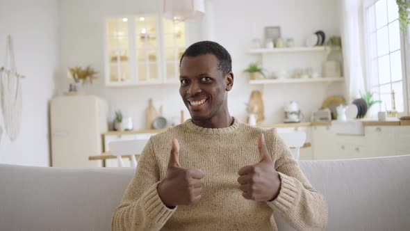 Funny African American Man Shows Thumbsup Sitting on Sofa alt