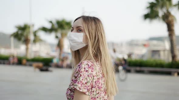Beautiful Woman in Dress and Medical Mask Walking Alone on City Pier alt