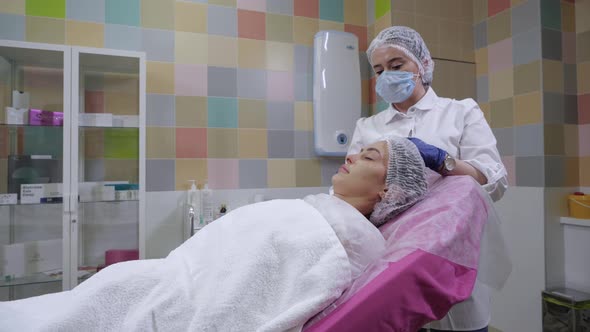 Beautician Wipes Young Woman's Face Before Being Given Filler Injections