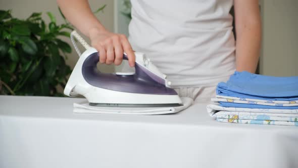 A Woman Irons a Baby Diaper with an Iron on an Ironing Board Closeup alt