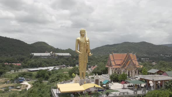 Huge Golden Buddha Statue standing on Hilltop next to Wat Khao Noi (Hua Hin), Orbiting Shot alt