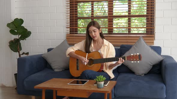 Girl Playing Guitar and Writing Song