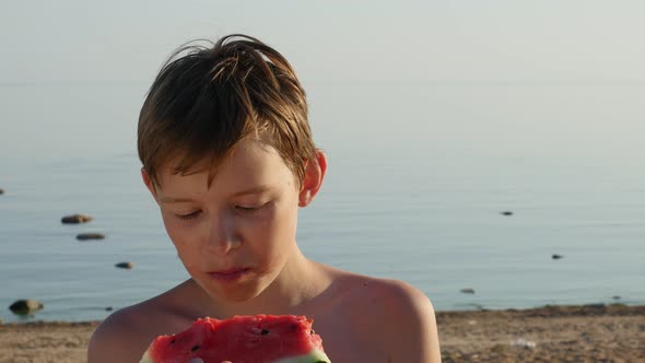 Teenage Boy Eating a Juicy Watermelon on the Beach