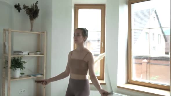 Young Girl in Sportswear Does Jump Exercise in Bright Room with Skipping Rope