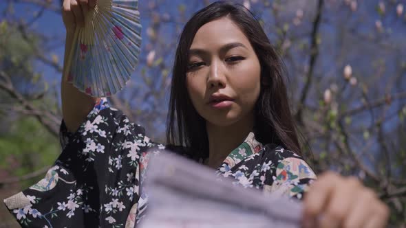 Closeup of Gorgeous Confident Asian Woman Dancing with Fans Looking at Camera alt