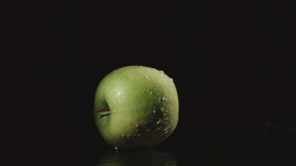 Apple Falls In Water In Dark And Splashes Scatter In Different Directions