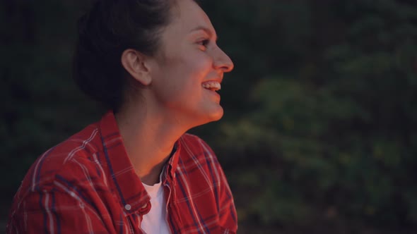 Close-up Portrait of Attractive Young Woman Tourist Sitting Near Campfire and Singing Songs Enjoying alt